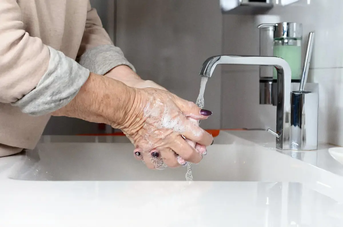Older woman washing her hands at a bathroom sink