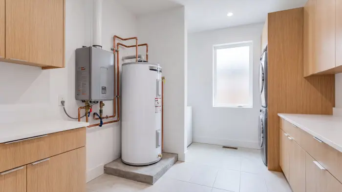 Tankless and tank water heaters installed in a bright laundry room