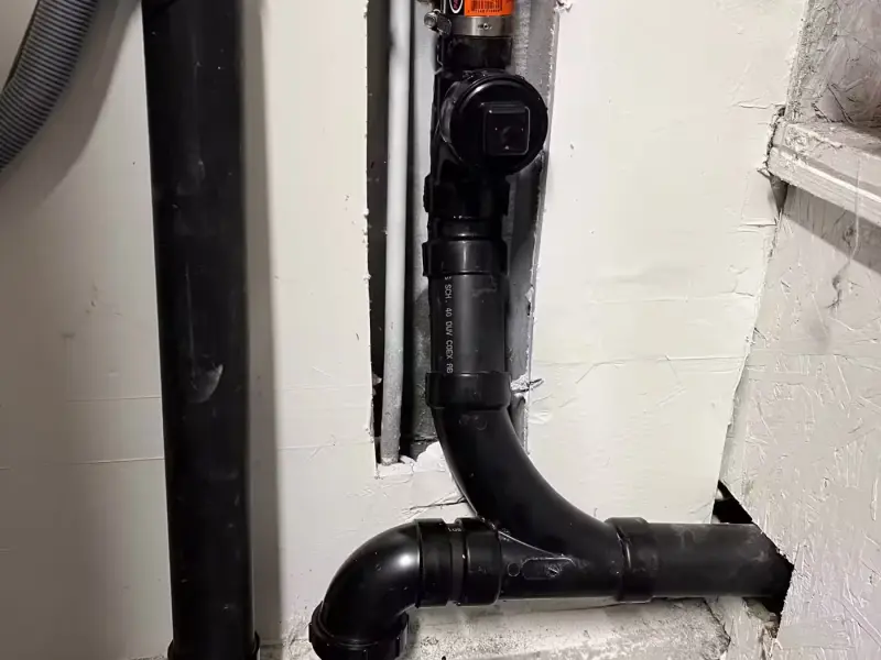 New black ABS drain line and cleanout fitting installed in an opened wall
