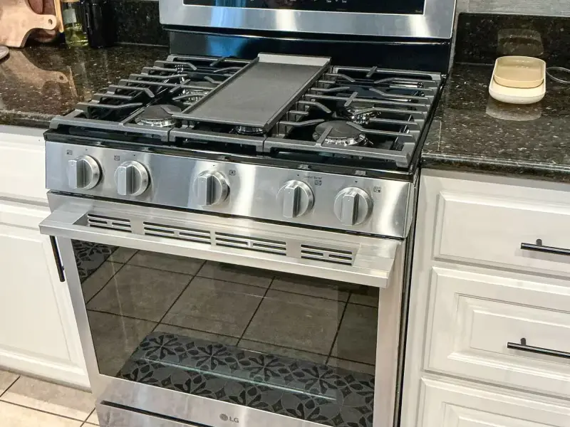 LG stainless steel gas range with center griddle installed between granite counters