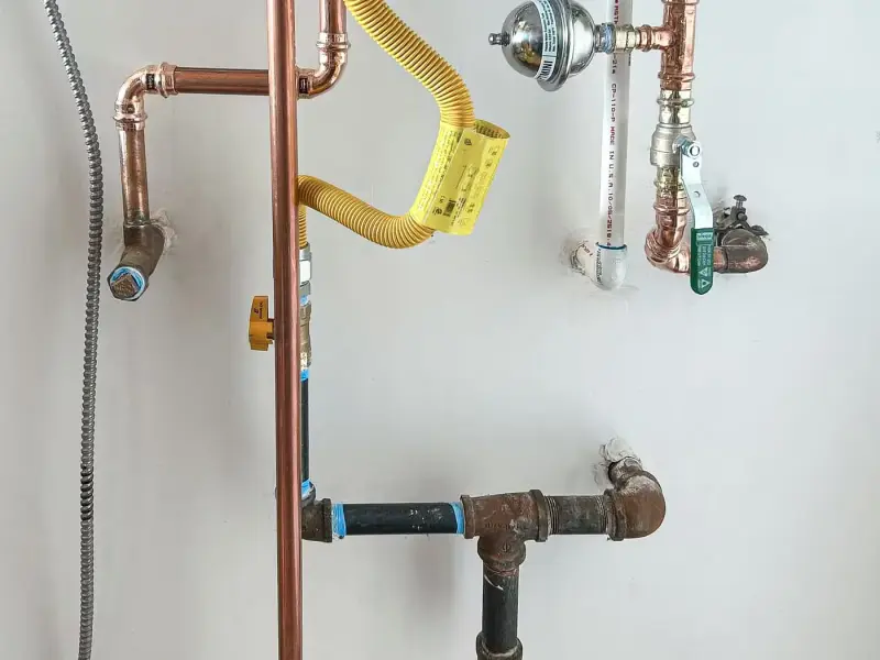 New copper water lines, yellow gas flex line and shutoff valves below a tankless water heater