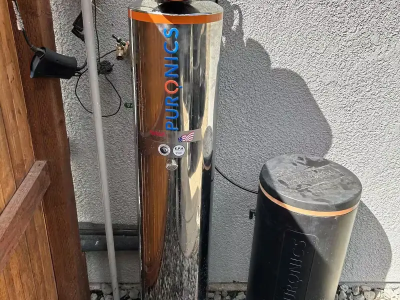 Puronics stainless water softener and brine tank installed outside a house