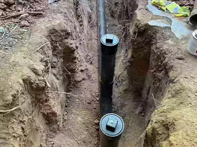 New black ABS sewer line with two cleanout risers laid in an open trench