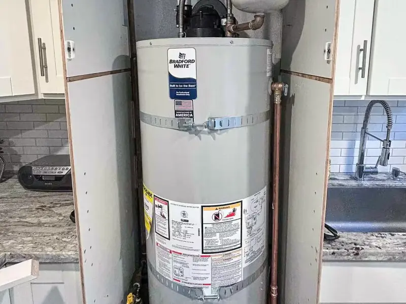 Bradford White gas water heater with expansion tank in a kitchen utility closet